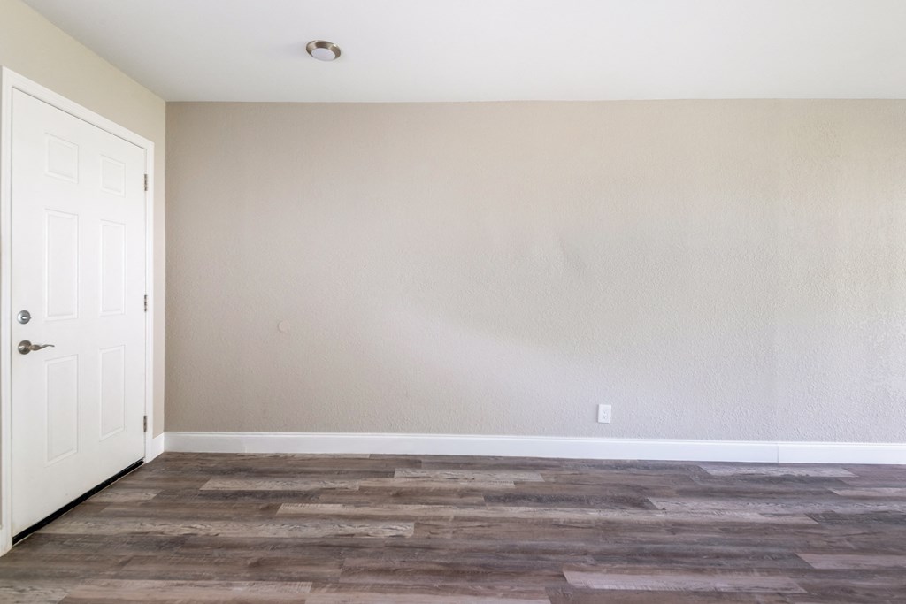 an empty room with wood floors and a white door at Palm Cove Apartments, Daytona Beach, FL 32114