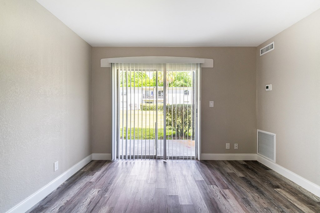 an empty living room with a sliding glass door to a balcony at Palm Cove Apartments, Daytona Beach, FL