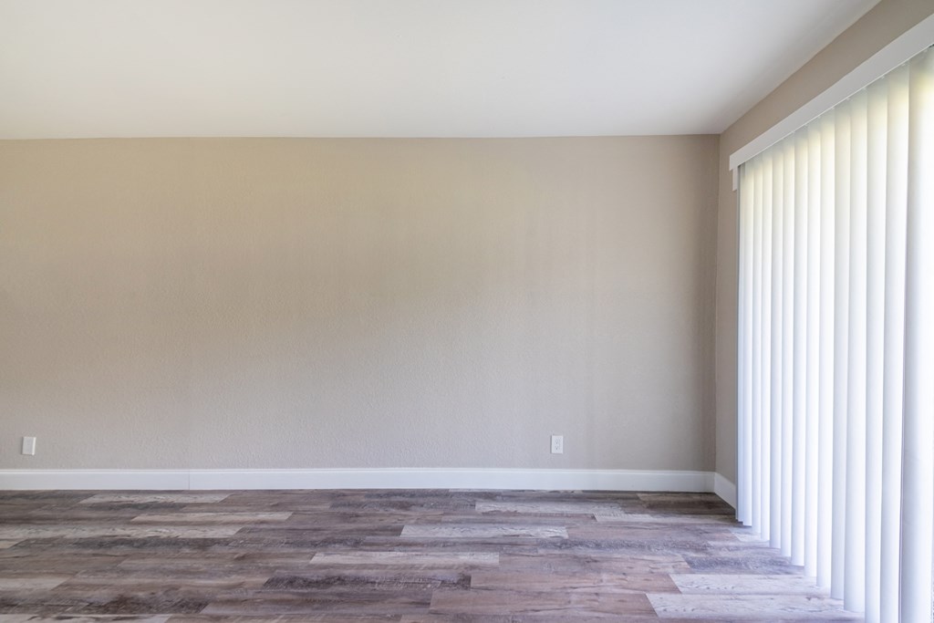 an empty room with white blinds and a wood floor at Palm Cove Apartments, Daytona Beach, FL 32114