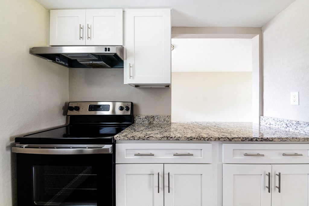 a kitchen with white cabinets and black appliances and granite counter tops at Palm Cove Apartments, Daytona Beach Florida