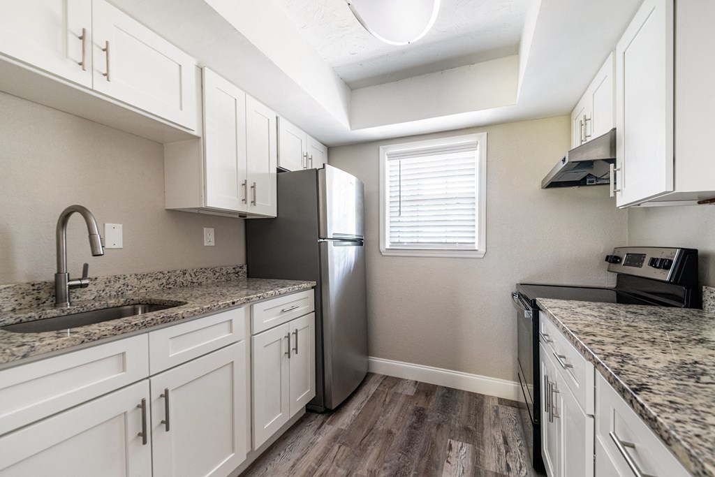a kitchen with white cabinets and granite counter tops and a stainless steel refrigerator at Palm Cove Apartments, Daytona Beach, FL 32114