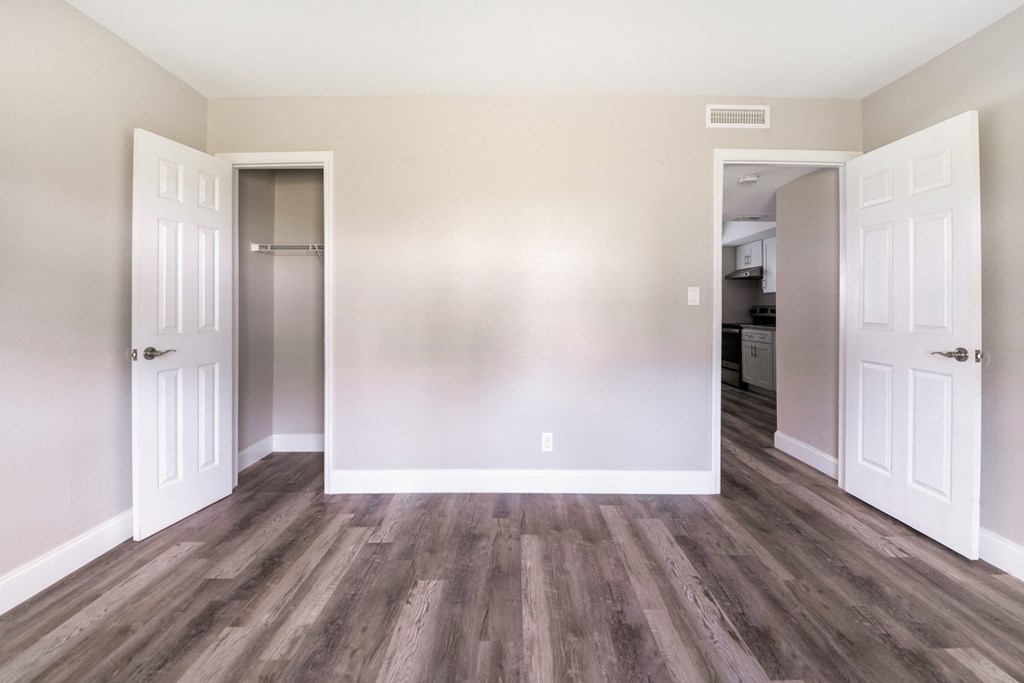 an empty living room with wood floors and white doors at Palm Cove Apartments, Daytona Beach, 32114 