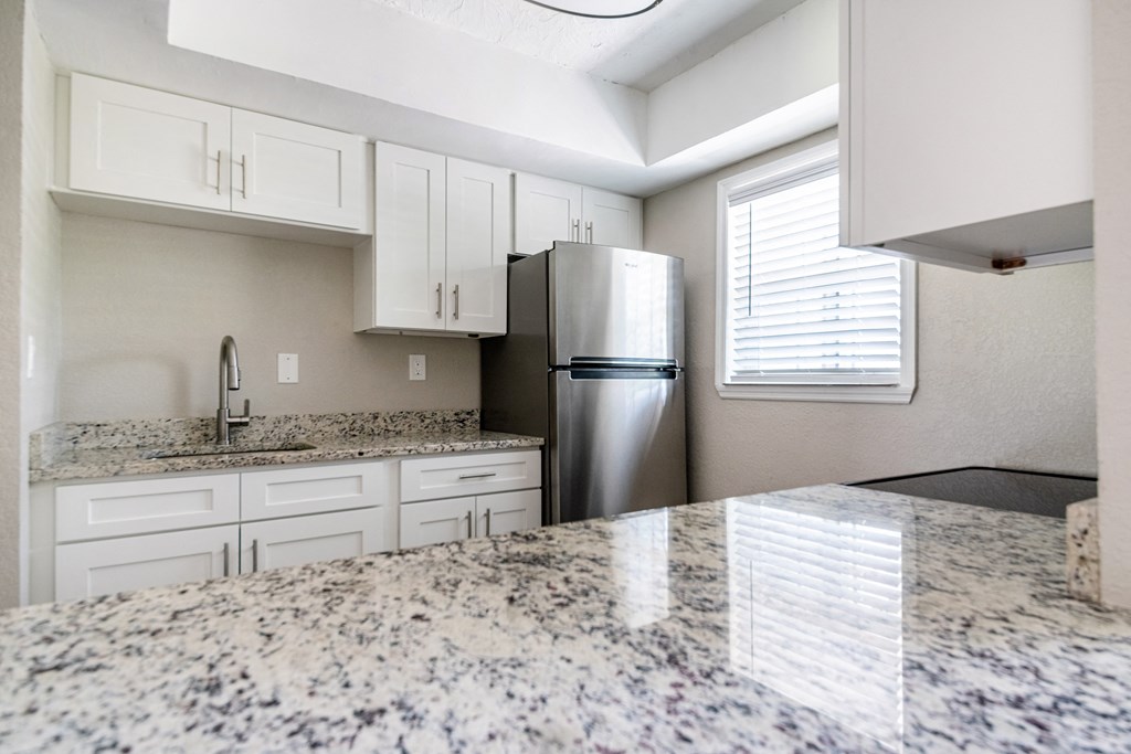 a kitchen with granite counter tops and a stainless steel refrigerator at Palm Cove Apartments, Daytona Beach, FL