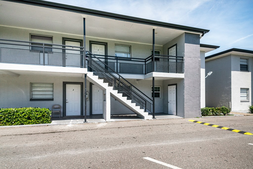 an exterior view of a building with stairs and a parking lot an exterior view of a building with stairs and a parking lot at Palm Cove Apartments, Daytona Beach Florida