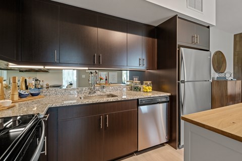 A modern kitchen with dark brown cabinets and stainless steel appliances.
