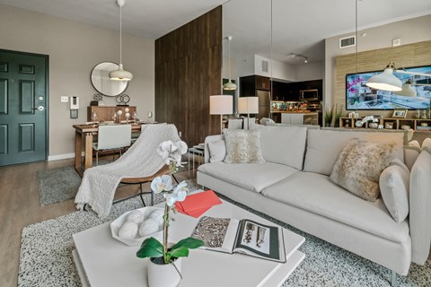 A living room with a white couch and a coffee table with a vase of flowers on it.