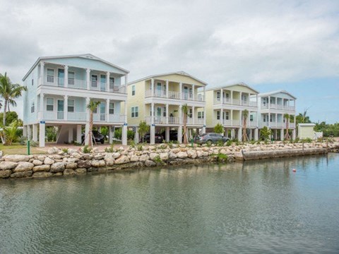 A row of beach houses are situated on a waterfront.
