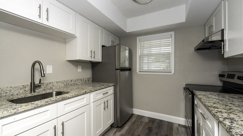 a kitchen with white cabinets and granite counter tops and a stainless steel refrigerator at Palm Cove Apartments, Florida, 32114