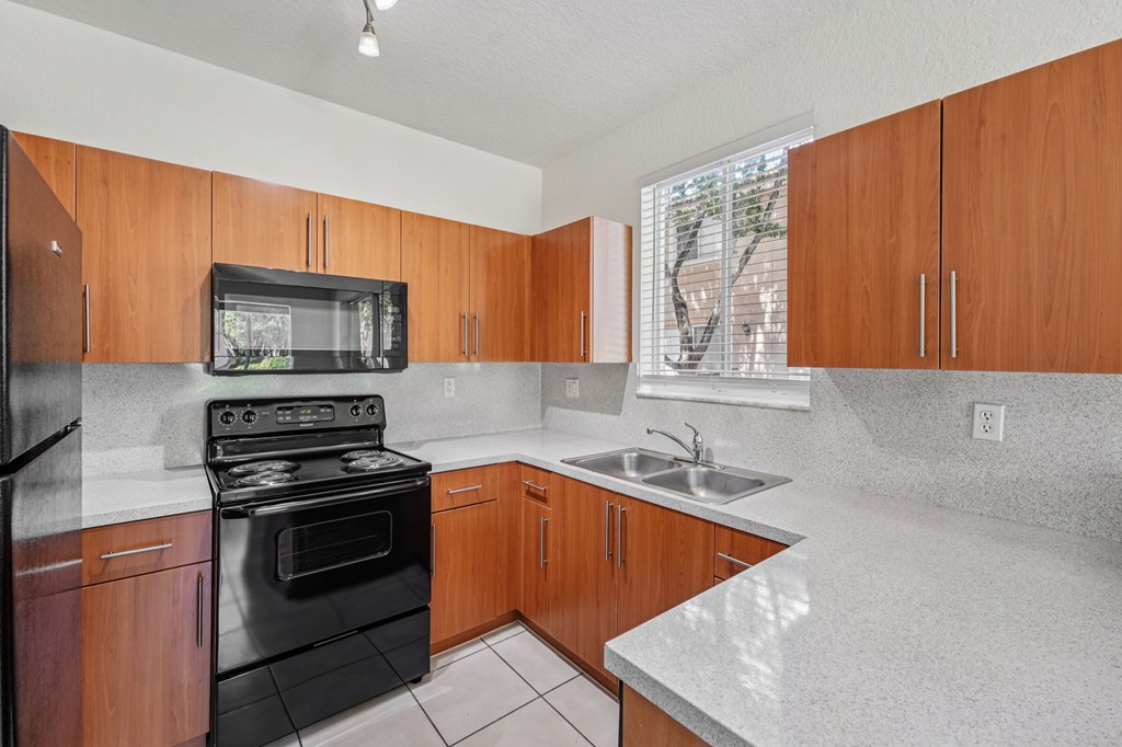 A kitchen with wooden cabinets and black appliances.