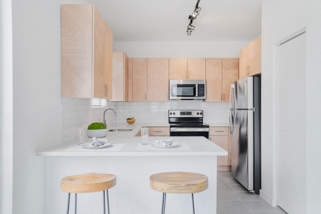 a kitchen with wooden cabinets and a white counter top with three stools