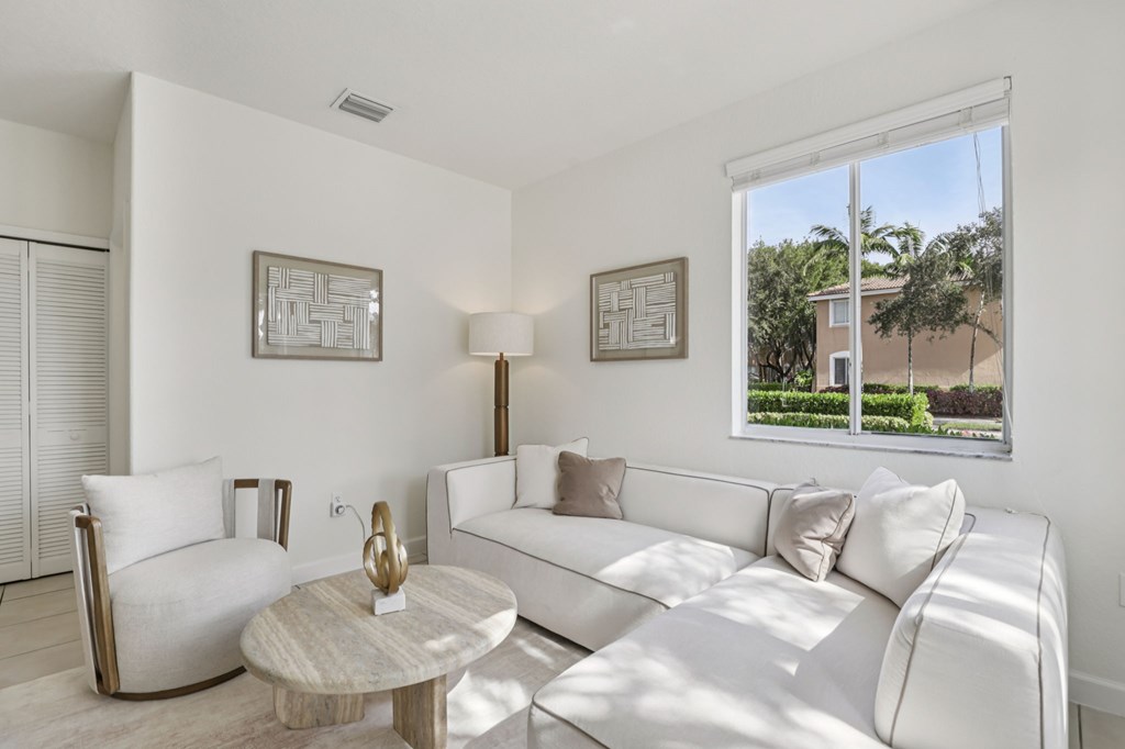 A living room with a white couch, a coffee table, and two chairs.
