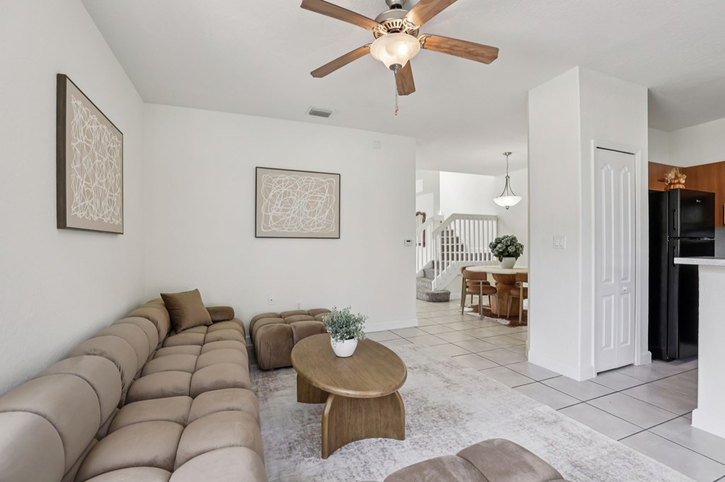 A living room with a brown couch and a ceiling fan.