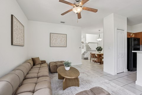A living room with a brown couch and a ceiling fan.