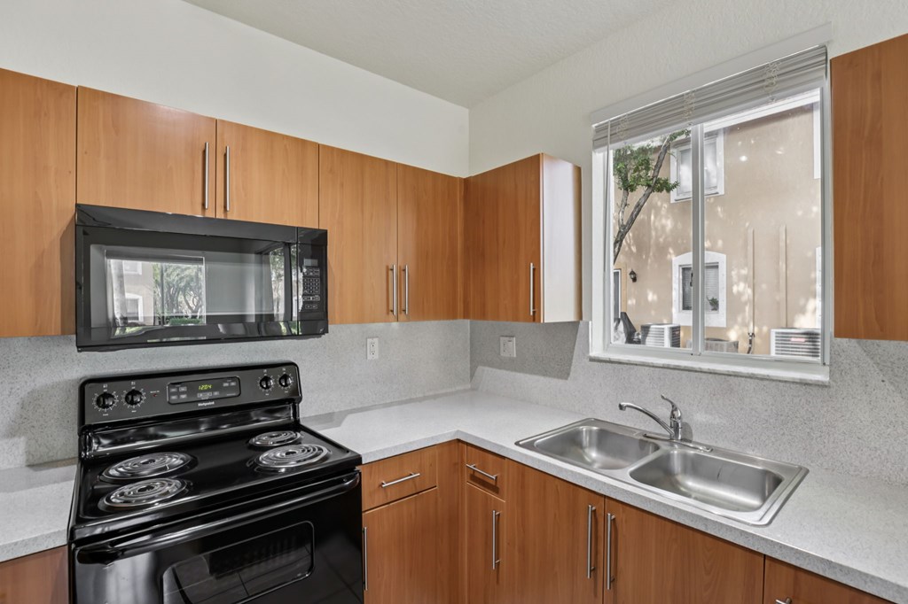 A kitchen with a black stove and wooden cabinets.