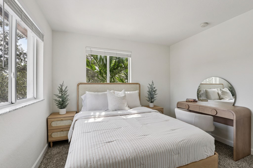 A bedroom with a large bed, a nightstand, and a mirror.