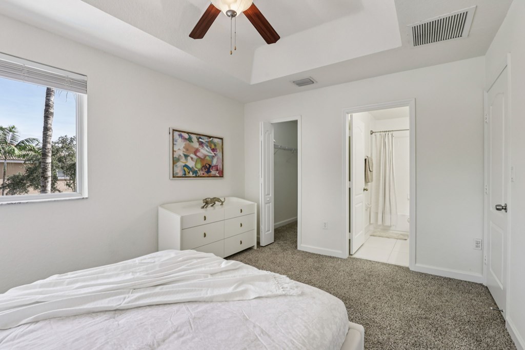 A bedroom with a bed, dresser, and a painting on the wall.