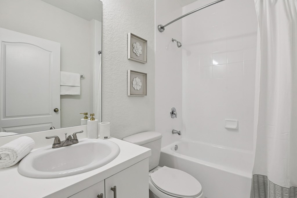 A white bathroom with a toilet, sink, and bathtub.