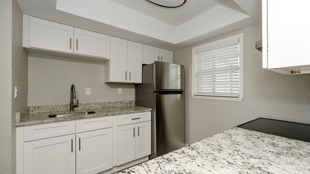 a kitchen with white cabinets and a stainless steel refrigerator at Palm Cove Apartments, Daytona Beach Florida