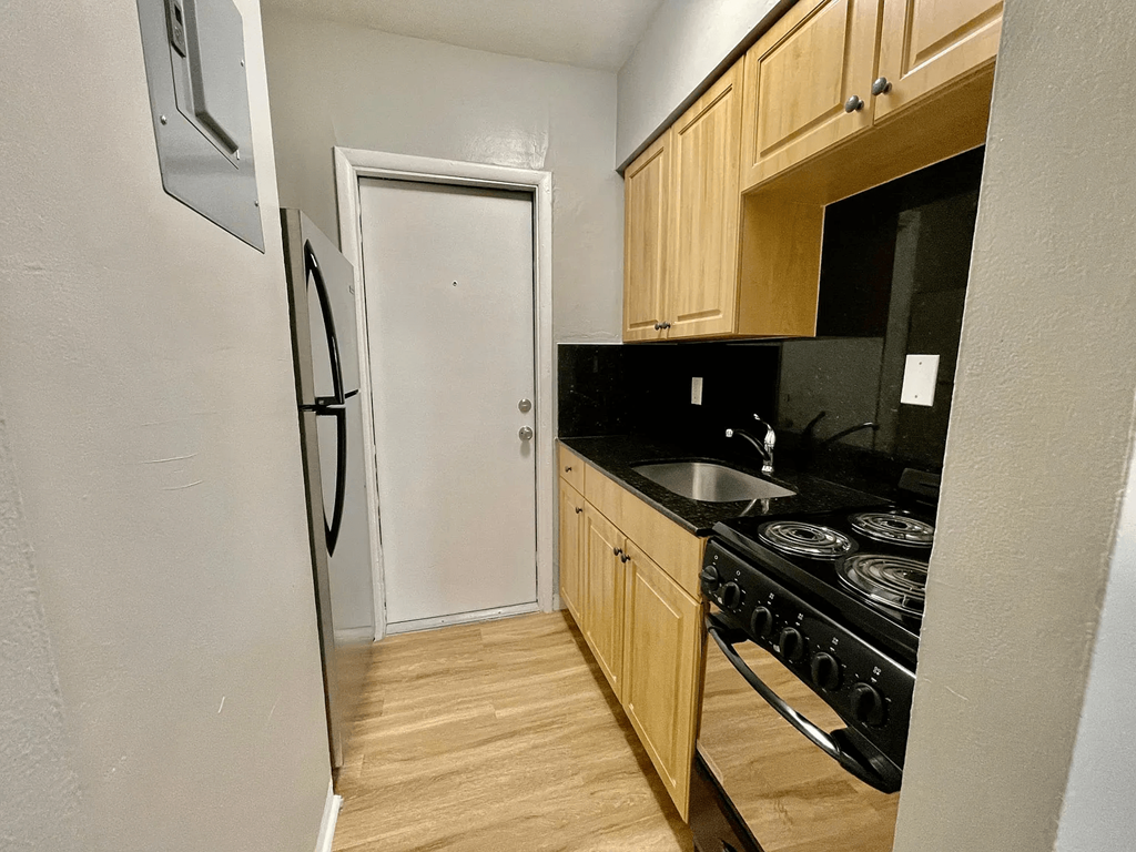 a kitchen with wooden cabinets and a black stove top oven at Lakeside @ Biscayne Gardens,North Miami,33181