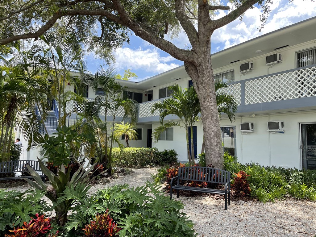 a bench sits in the middle of a garden in front of a building at Lakeside @ Biscayne Gardens,North Miami,33181