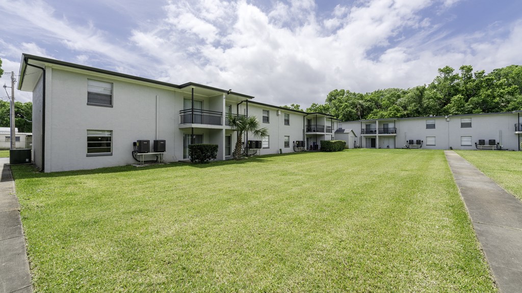 the outlook of an apartment building with a large grass yard at Palm Cove Apartments, Florida