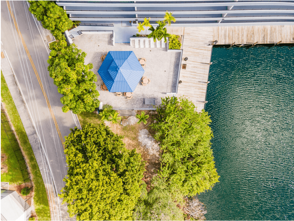 an aerial view of a house with a blue umbrella next to a body of water at Lakeside @ Biscayne Gardens,North Miami