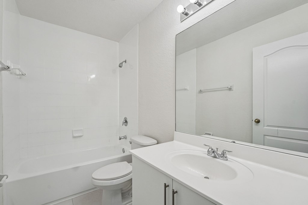 A white bathroom with a toilet, sink, and mirror.
