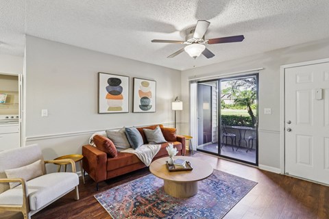 A living room with a brown couch and a ceiling fan.