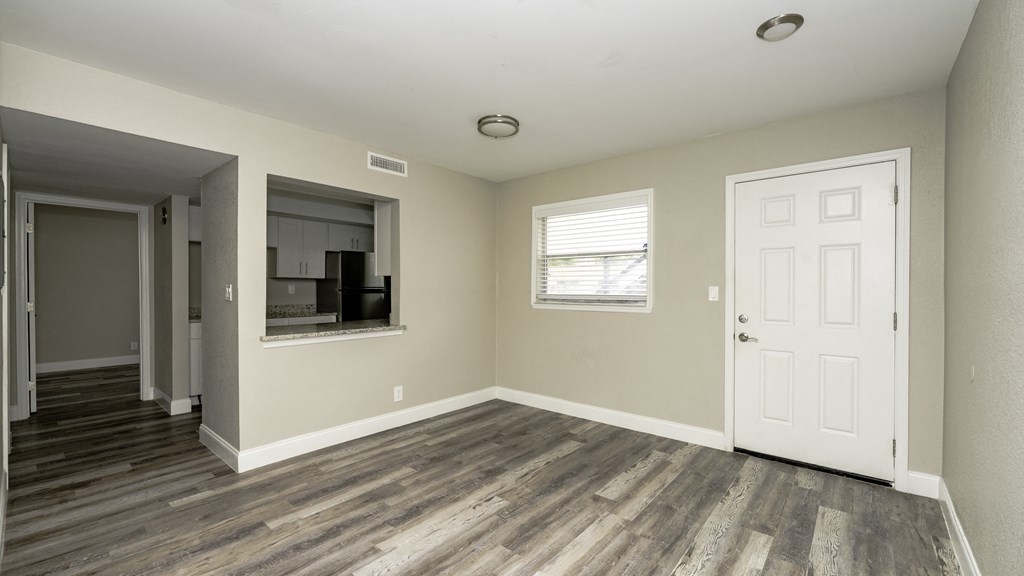 the living room and dining room of an apartment with wooden floors and a white door at Palm Cove Apartments, Daytona Beach, FL
