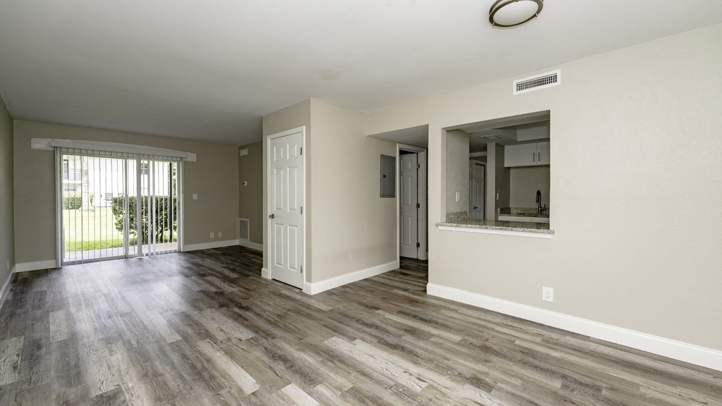 an empty living room with wood flooring and a sliding glass door at Palm Cove Apartments, Daytona Beach, 32114