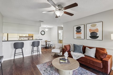 A living room with a brown couch, a coffee table, and a ceiling fan.