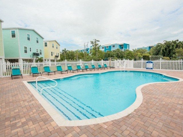 A small pool with a brick border and a white fence.