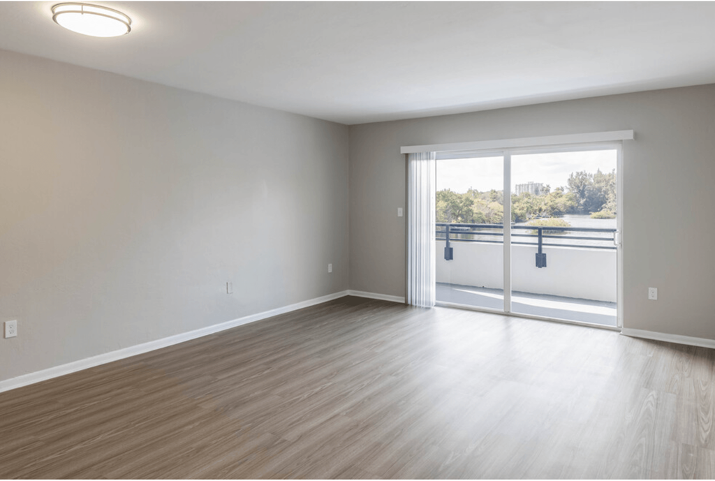 an empty living room with a sliding glass door leading to a balcony at Lakeside @ Biscayne Gardens,North Miami, Florida
