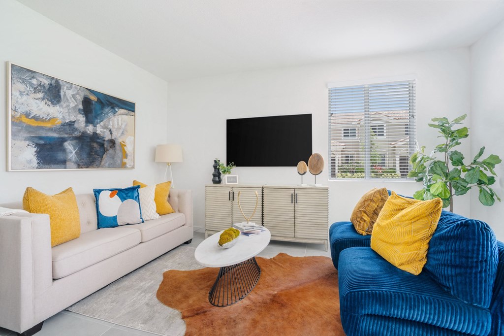 two couches and a coffee table in a living room with a tv on the wall