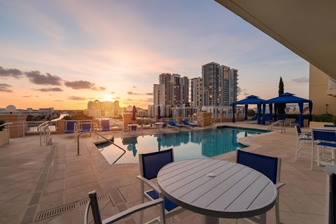 A sunset view of a pool area with a table and chairs.
