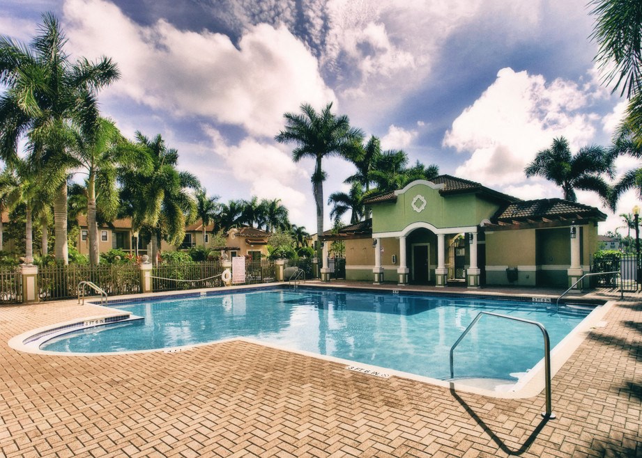 a swimming pool with palm trees in front of a house