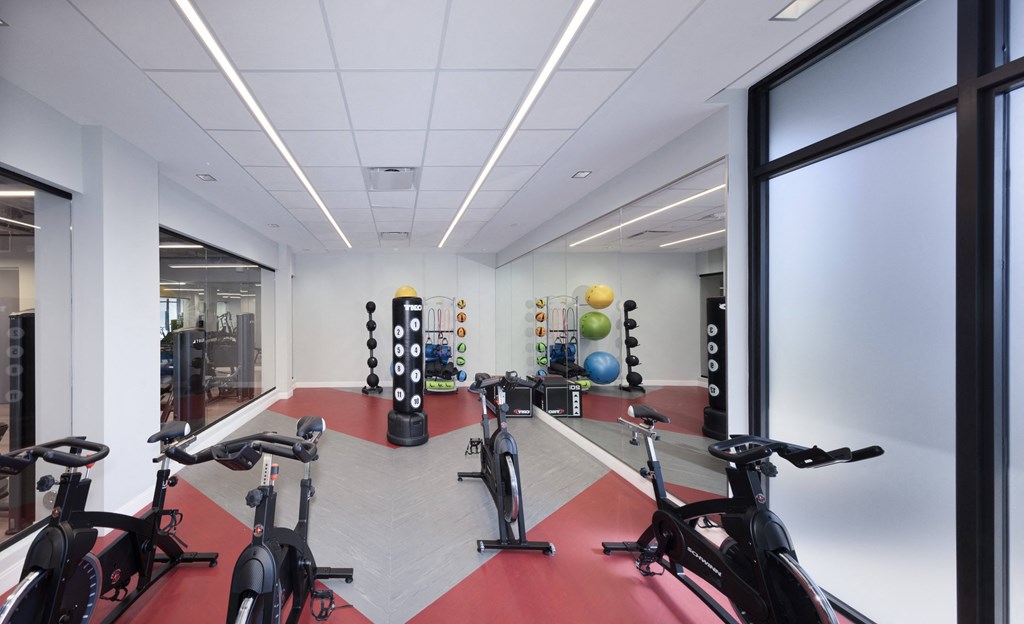A gym with exercise bikes and a red floor.