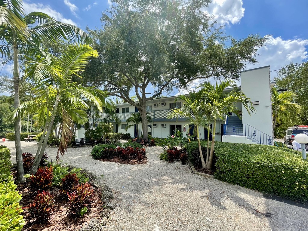 a large white building with a tree in front of it at Lakeside @ Biscayne Gardens, North Miami, Florida, 33181