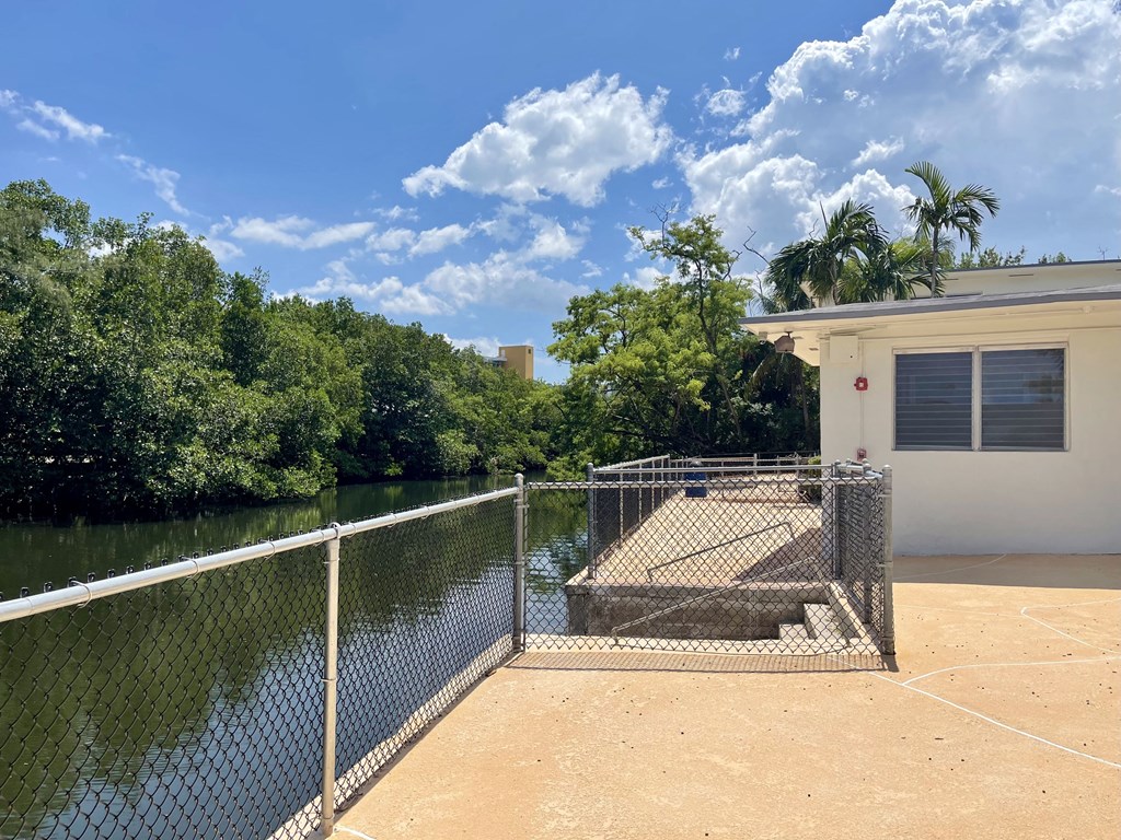 a fenced in area with a body of water in front of a house at Lakeside @ Biscayne Gardens,North Miami, Florida