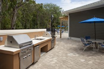 A patio with a grill and chairs.