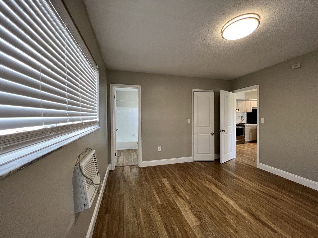 an empty living room with a large window and wood flooring  at Palm Gardens @ Biscayne Gardens, Florida, 33181