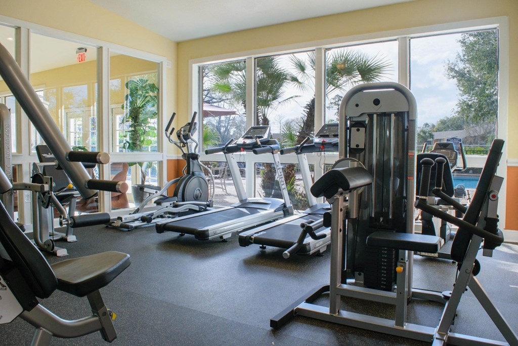 a gym with cardio equipment and a pool in the background at Lakeside Gardens, Daytona, 32114