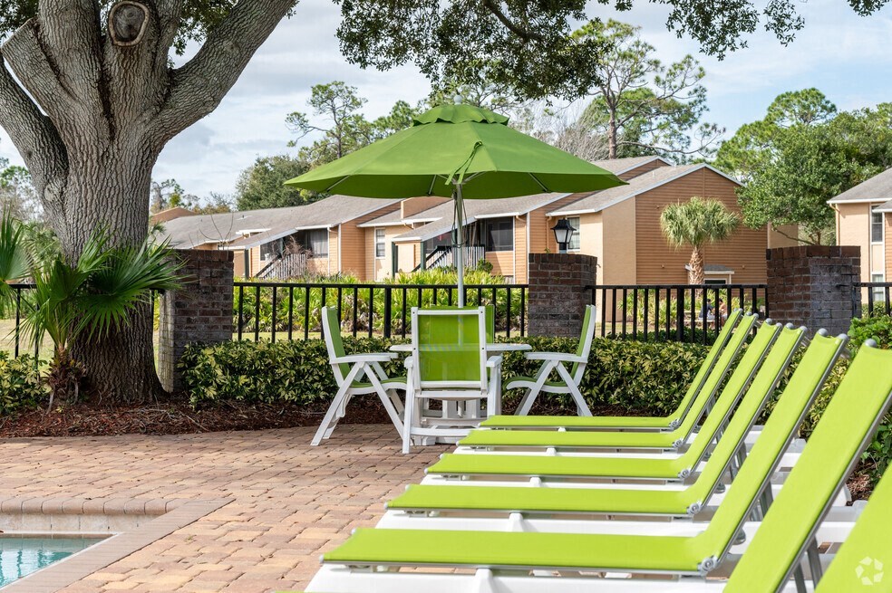 a group of lawn chairs and umbrellas sitting next to a pool at Lakeside Gardens, Daytona