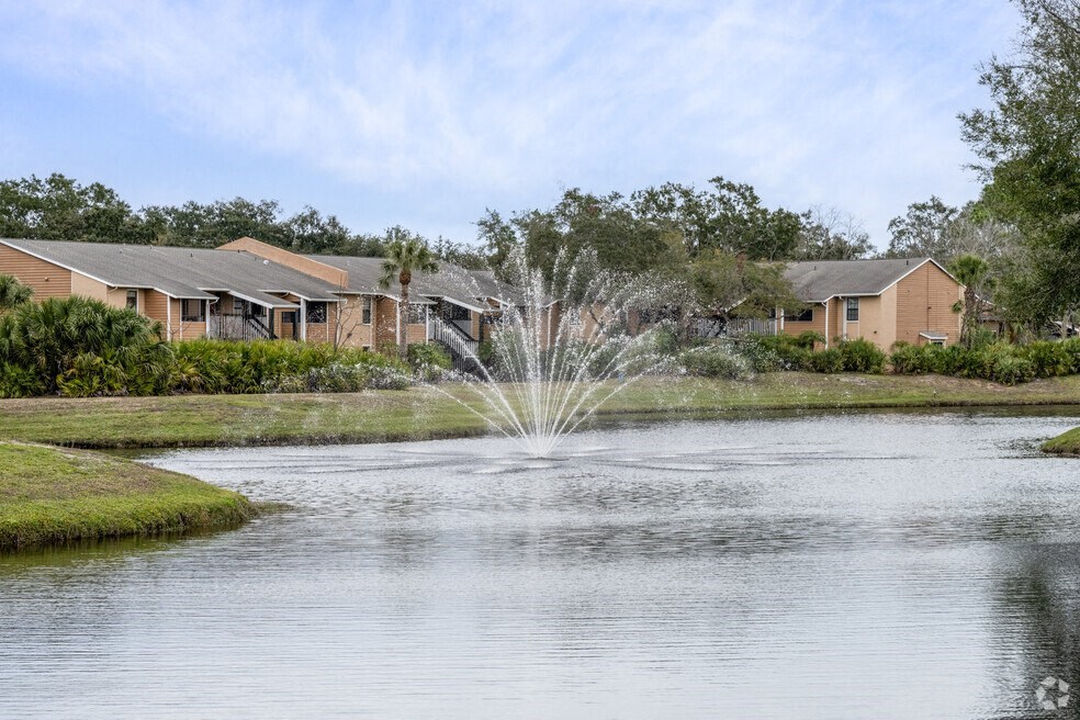 a fountain in the middle of a pond with houses in the background at Lakeside Gardens, Daytona, 32114