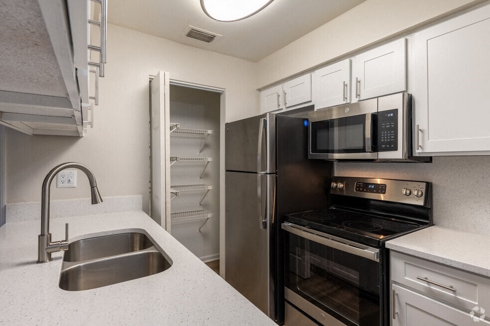 a kitchen with stainless steel appliances and white cabinets a kitchen with stainless steel appliances and white cabinets at Lakeside Gardens, Daytona, FL