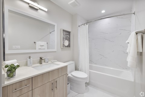 A white bathroom with a marble wall and a towel hanging on the hook.