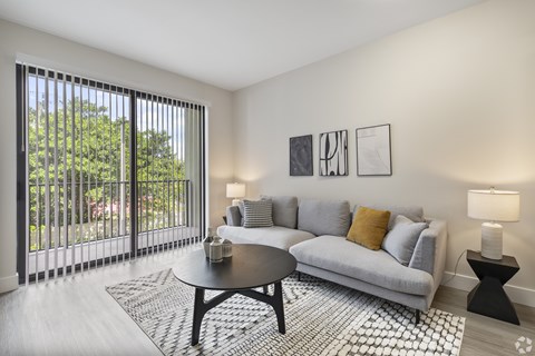 A living room with a grey couch, a coffee table, and a lamp.
