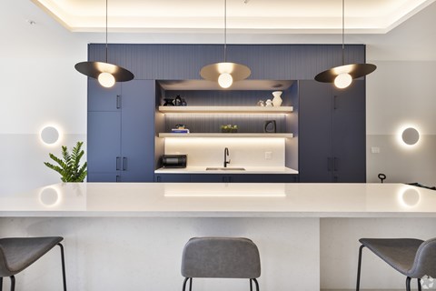 A modern kitchen with a white countertop and grey chairs.