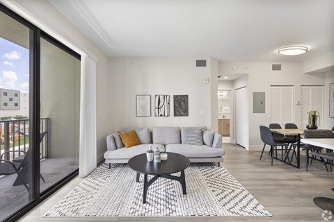 A modern living room with a glass door leading to a balcony.