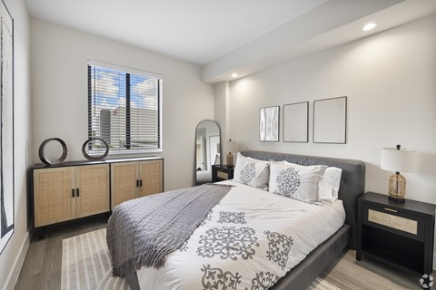 A bedroom with a large bed and a window with blinds.
